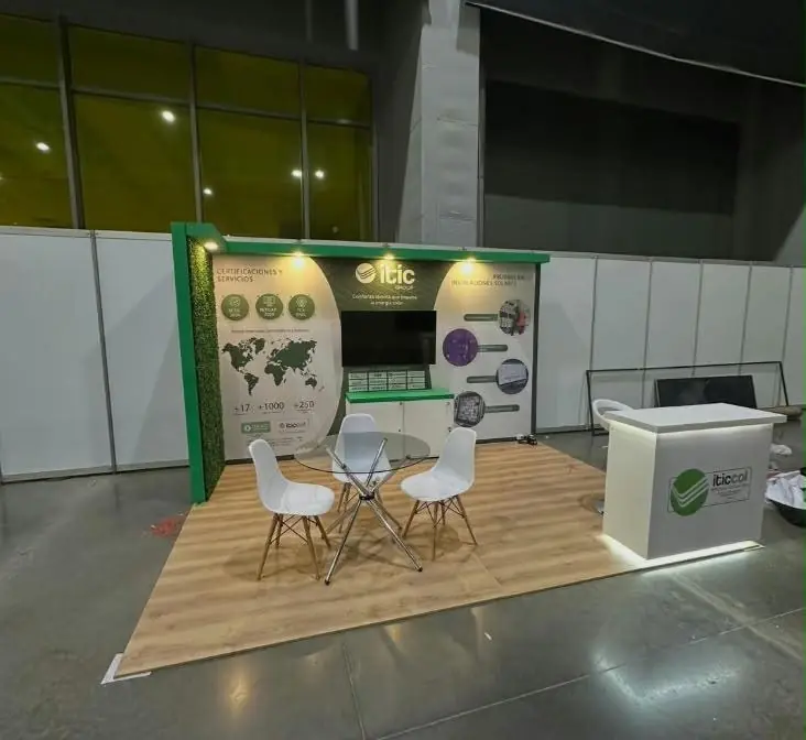 Stand de feria con piso de madera, pared gráfica con pantalla, mesa de reuniones y counter iluminado