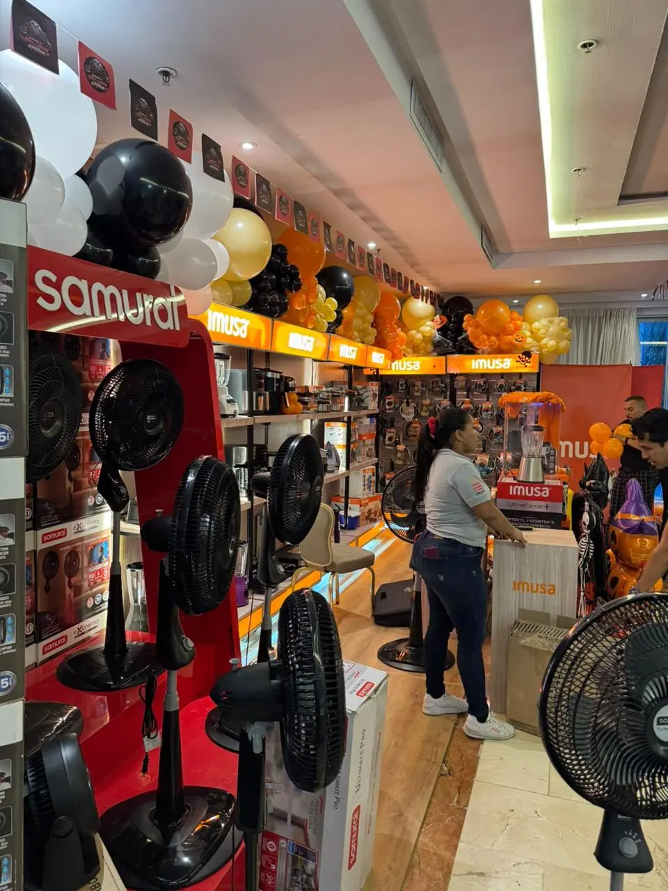 Exhibición de marca con avisos luminosos, estanterías de producto y decoración con globos