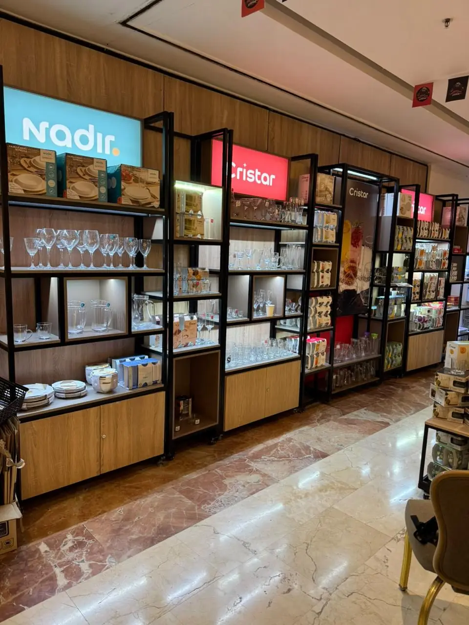 Exhibición comercial con estanterías iluminadas y avisos de marca para cristalería