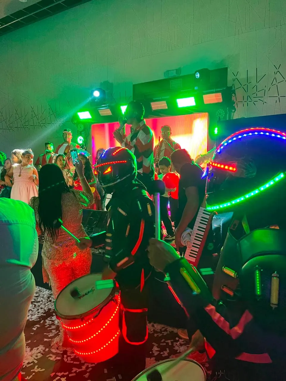 Hora loca con personajes en trajes de luces LED y tambores luminosos animando la fiesta